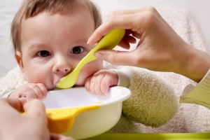 young mother feeding baby baby food with a spoon