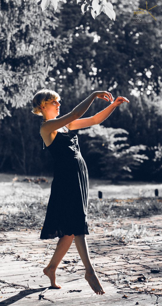 Młoda kobieta w czarnej krótkiej sukience tańczy
